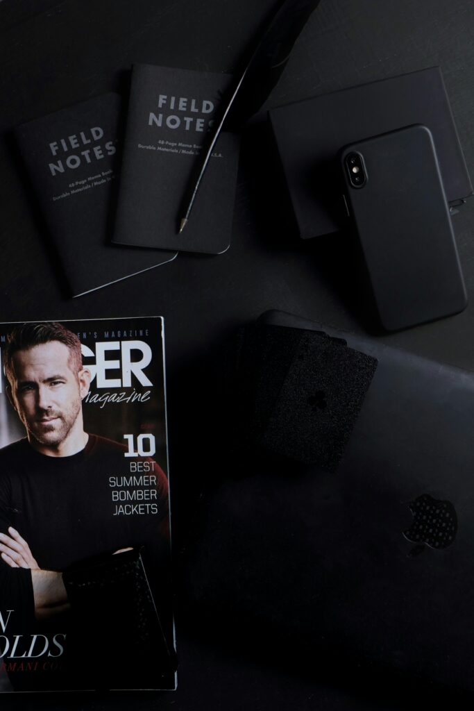 A minimalist workspace featuring a smartphone, notebooks, and a magazine, perfect for business and lifestyle themes.